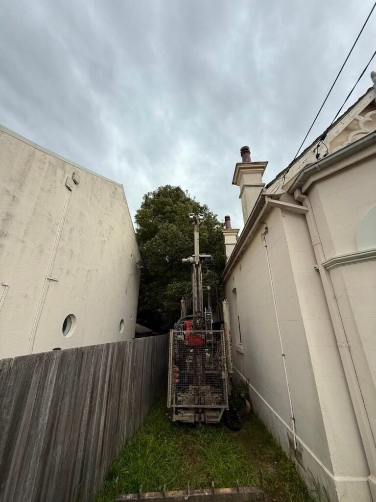 Track-mounted drilling rig working in narrow access between buildings, Burwood NSW